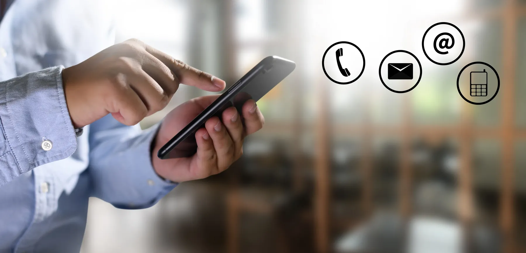 A person using a mobile phone beside icons representing telephone, email and messaging contact options