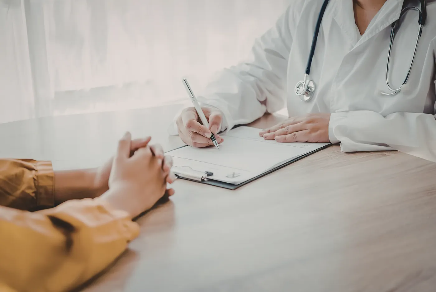 A practitioner and client seated across a desk during an initial consultation conversation
